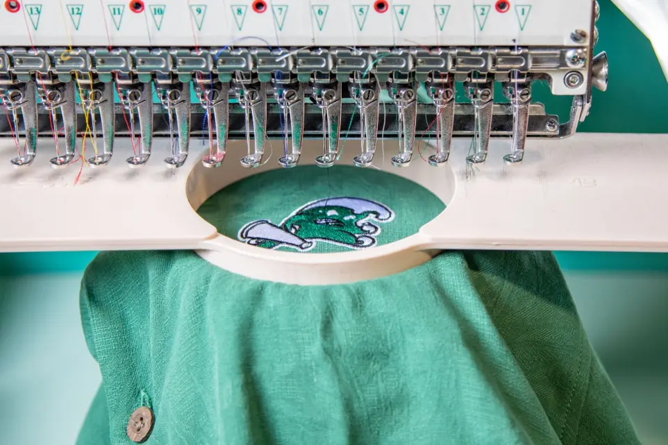 Premium Embroidery Services for Custom Apparel Embroidery machine stitching a custom logo on a polo shirt